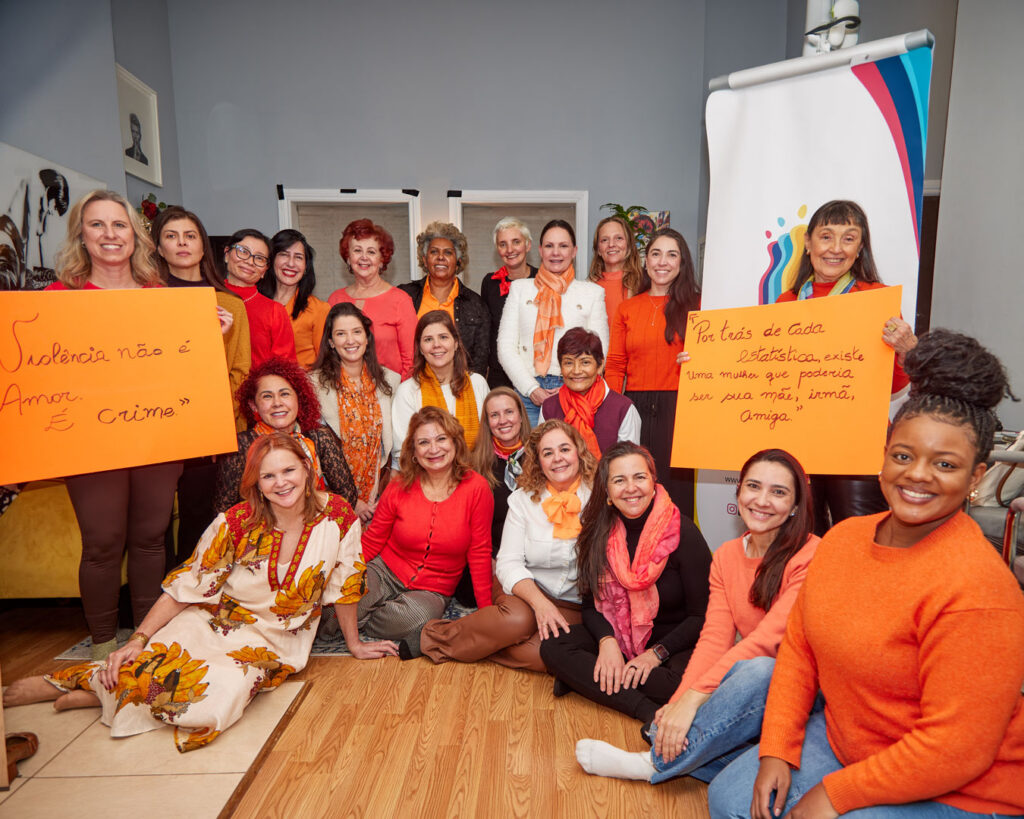 Grupo de mulheres reunidas para uma foto segurando cartazes de conscientização contra a violência.